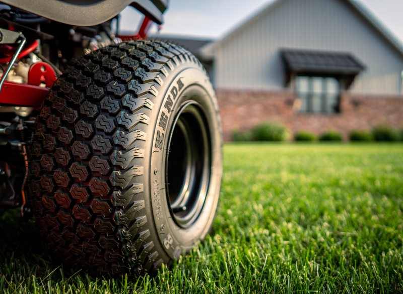 Routine Yard Maintenance with Gas-Powered Mower Person mowing green grass with a heavy-duty riding mower.